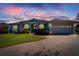 Gray house with a three-car garage, and a brick driveway under a sunset sky at 7068 Island Lake Ln, Lakeland, FL 33813