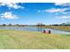 Serene view of a lake and golf course with red Adirondack chairs at 7068 Island Lake Ln, Lakeland, FL 33813