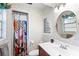 Cozy bathroom with colorful shower curtain, round mirror, and floral-patterned wallpaper at 123 Padgett N Pl, Lakeland, FL 33809