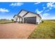 Contemporary farmhouse design with a black garage door and brick driveway at 2200 Mcclellan Rd, Frostproof, FL 33843