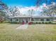 Inviting single-story home with a brick pathway, surrounded by lush greenery and mature trees, offering a serene setting at 2720 Ewell Rd, Lakeland, FL 33811