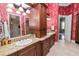 Double vanity bathroom with granite counters, a large shower, and red floral wallpaper at 2961 Sanctuary Cir, Lakeland, FL 33803