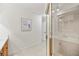 Bright, tiled bathroom features a walk-in shower with a gold frame, and an adjacent hall with a white door at 4718 Valley Hill Ct, Lakeland, FL 33813