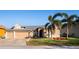 Tan three-car garage house with palm trees and manicured lawn at 518 Grand Reserve Dr, Davenport, FL 33837