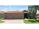 Tan two-car garage home with a landscaped lawn and palm tree at 5269 Pebble Beach Blvd, Winter Haven, FL 33884