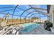 Enclosed pool with a screen enclosure, two lounge chairs, a grill, and an outdoor dining set at 5440 Siltstone St, Lakeland, FL 33811