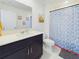 Well-lit bathroom featuring a vanity with dark cabinets, white countertop, toilet and a shower with a decorative blue curtain at 951 Craftsman Rd, Eagle Lake, FL 33839