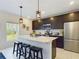 Modern kitchen with stainless steel appliances, dark cabinets, an island with seating, and stylish pendant lighting at 951 Craftsman Rd, Eagle Lake, FL 33839