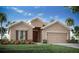 Single-story home with a light beige exterior, brown accents, and a two-car garage at 1104 Mountain Flower Ln, Davenport, FL 33837