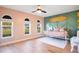 A bedroom with light pink walls, a small white daybed, three windows, and light colored wood flooring at 1325 Fairlee St, Lakeland, FL 33813