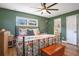 This green-walled bedroom has a floral bedspread, a ceiling fan, and a glimpse into the en suite bathroom at 1325 Fairlee St, Lakeland, FL 33813