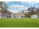 Rear exterior of a home with large windows, a screened-in porch, an outbuilding, and a spacious lawn for outdoor enjoyment at 20 N Lake Idylwild Dr, Winter Haven, FL 33881