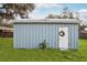 A light blue tool shed with a white door and decorative wreath on a spacious lawn at 20 N Lake Idylwild Dr, Winter Haven, FL 33881