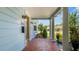 Inviting front porch featuring red tile flooring, stately white pillars, and vintage sconce lighting at 2016 Seminole Trl, Lakeland, FL 33803