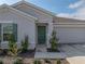 Charming home featuring a green front door, neutral stucco, and a two-car garage enhancing curb appeal at 34575 Shellback St, Leesburg, FL 34788