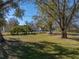 Large backyard with mature trees and grassy area at 702 Nw 1St Ave, Mulberry, FL 33860