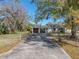 House with carport and gated driveway, surrounded by mature trees at 702 Nw 1St Ave, Mulberry, FL 33860