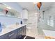 Bathroom featuring double sink vanity and a seamless glass shower with white and grey veined marble-look tile at 751 Meandering Way, Polk City, FL 33868