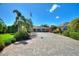 Long brick driveway leading to a charming home with lush, tropical landscaping at 751 Meandering Way, Polk City, FL 33868