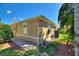 Tan home exterior with paver walkway, green lawn, palm tree, and landscaping at 751 Meandering Way, Polk City, FL 33868