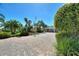 Expansive brick driveway with palm trees and lush tropical landscaping at 751 Meandering Way, Polk City, FL 33868