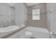 Bright bathroom with a white tub, tiled wall and a single sink vanity with a light-toned countertop at 1065 Silas St, Haines City, FL 33844