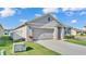 View of the home's facade, featuring a two-car garage, and a neatly kept lawn with landscaping at 1878 Pristine Loop, Lakeland, FL 33811