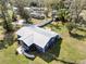 Aerial view of a cozy blue home featuring a metal roof and expansive green lawn at 3920 Timberlake E Rd, Lakeland, FL 33810