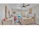 Bright bedroom featuring a ceiling fan, a large bed with patterned bedding, and a cozy pink chair by the window at 4145 Whistlewood Cir, Lakeland, FL 33811