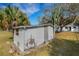 Shed exterior with white siding, peeling paint, a wooden door, and palm trees around the property at 4380 Turner Rd, Mulberry, FL 33860