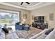 Bright living room featuring comfy sofas, large TV, and sliding glass doors to backyard at 4434 Micanope Crescent Dr, Lakeland, FL 33811