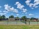 A community tennis court is featured with lush green surroundings and a bright blue sky at 4434 Micanope Crescent Dr, Lakeland, FL 33811