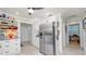 Bright kitchen featuring a stainless steel refrigerator, white cabinets, and decorative shelving with colorful dishware at 531 Hunter St, Lakeland, FL 33803