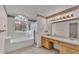 Bright bathroom featuring double sinks, a separate shower, and a tub with a large arched window at 6244 Napa Dr, Lakeland, FL 33813