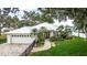 Beautiful home with a white exterior, metal roof, brick driveway, and mature landscaping in a lakeside setting at 739 Swann Dr, Lakeland, FL 33809