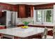 Close-up of kitchen island featuring white countertop, cherry cabinets, and stainless steel refrigerator at 739 Swann Dr, Lakeland, FL 33809