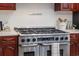 Close-up of a stainless steel gas range oven with cherry cabinets and white countertops at 739 Swann Dr, Lakeland, FL 33809