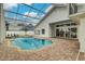 Screened-in pool area, with brick paver deck, lush landscaping, and partial lake view at 739 Swann Dr, Lakeland, FL 33809