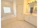 Relaxing bathroom featuring a soaking tub, white cabinets, and a large mirror with vanity lighting at 103 Paleo Point Ct, Winter Haven, FL 33880