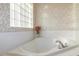 Bright bathroom featuring a large soaking tub, flower accent, and a window with glass blocks for natural light at 1961 Rocky Pointe Dr, Lakeland, FL 33813