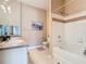 Bright bathroom featuring a dual sink vanity, bath tub with shower and warm neutral colored walls at 205 Terrace Ridge Cir # 205, Davenport, FL 33896