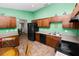 The green-walled kitchen features tile floors, wooden cabinets, black appliances, and breakfast table at 2160 Country Manor St, Bartow, FL 33830