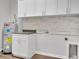 Bright laundry room featuring white cabinets, stacked stone backsplash, and modern fixtures at 4071 Magnolia Se Ave, Highland City, FL 33846