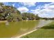 Scenic backyard view features a serene pond, lush green grass, and mature trees, creating a tranquil outdoor space at 4932 St James St, Winter Haven, FL 33881