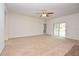 Spacious living room featuring neutral carpet, a ceiling fan, and sliding glass doors that provide backyard access at 4932 St James St, Winter Haven, FL 33881