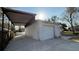 View of detached garage featuring a double garage door, white brickwork, and private driveway with carport at 495 King St, Haines City, FL 33844
