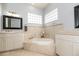 Luxurious bathroom featuring a soaking tub, marble accents, tiled floors, and dual vanities with white cabinets at 5155 Lake Deeson Woods Ct, Lakeland, FL 33805
