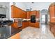 Well-lit kitchen featuring wood cabinets, black countertops, tile flooring, and stainless steel appliances at 5155 Lake Deeson Woods Ct, Lakeland, FL 33805