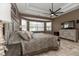 Cozy main bedroom featuring a tray ceiling, decorative fan, neutral paint, and tiled floors at 5155 Lake Deeson Woods Ct, Lakeland, FL 33805