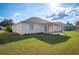 The backyard has a covered patio and large lawn with neutral siding and dark roofline at 519 Eagle Ct, Kissimmee, FL 34759